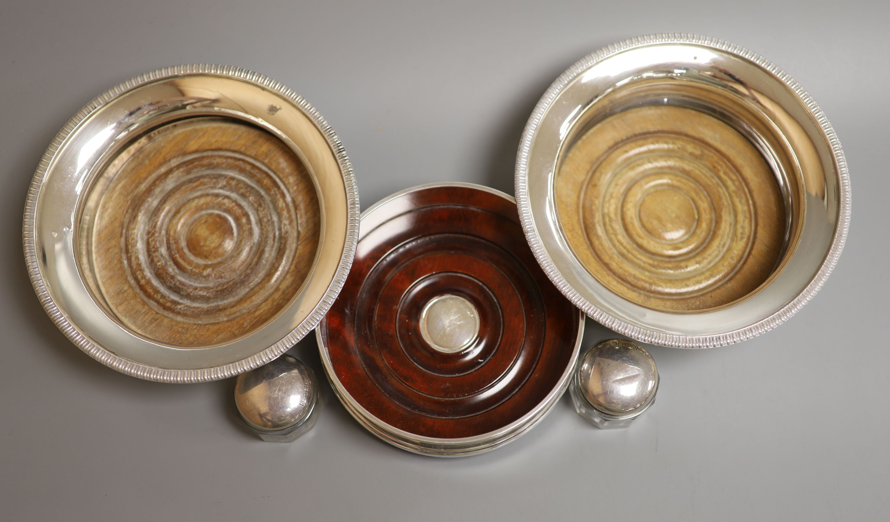 A modern pair of silver mounted wine coasters, J.B. Chatterley & Sons Ltd, Birmingham 1968, diameter 15.7cm (one wooden base loose), one other modern silver mounted wine coaster and a pair of George V silver mounted glas